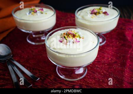 RAS Malai Mousse serviert in Glasdesserts: Indische Fusion Desserts mit Sahne, Safran und Nüssen, garniert mit Pistazien und Rosenblättern Stockfoto