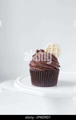 Schokoladen-Cupcake mit dunkler Schokoladen-Buttercreme, doppelte Schokoladen-Cupcakes mit amerikanischer Buttercreme, große Glasur auf einem Cupcake mit einer Waffel Stockfoto