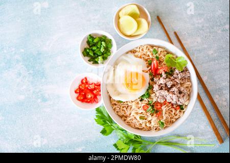 Nudelschüssel mit gekochtem Ei Hackfleisch Schweinefleisch Gemüse Frühlingszwiebeln Zitrone Limette Salat Sellerie und Chili auf dem Tisch, Nudelsuppe Instant Nudeln kochen Stockfoto