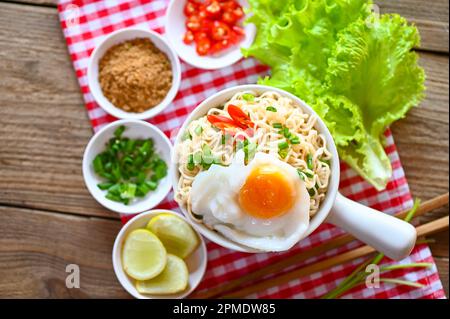 Nudelschüssel mit gekochtem Ei Hackfleisch Schweinefleisch Gemüse Frühlingszwiebeln Zitrone Limette Salat Sellerie und Chili auf dem Tisch, Nudelsuppe Instant Nudeln kochen Stockfoto