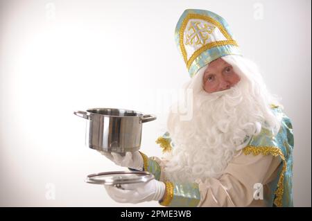Er hat einen türkisfarbenen und goldenen Anzug, einen langen weißen Bart und einen Hut mit einem kreuz, der wie ein Wintermonat aus einem märchenhaften Sinterklaas-Porträt aussieht. USA auf weißem Hintergrund. Holländischer Weihnachtsmann St. Nikolaus Stockfoto