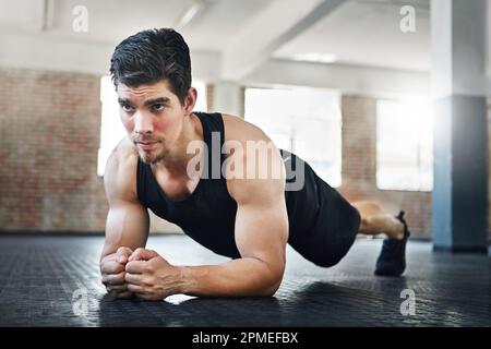 Auf seine Form fokussiert. Ein junger Sportler, der im Fitnessstudio trainiert. Stockfoto