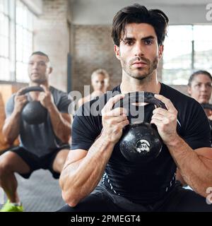 Für den Fall, dass es nicht genug brennt. Eine Gruppe von Leuten, die mit einer Wasserkessel-Glocke in einem Fitnessraum Squats machen. Stockfoto