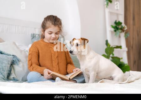 Glückliche mutter und Tochter spielen mit ihrem niedlichen verkabelten Jack Russell Terrier Welpen zu Hause. Liebevolle Familie mit einem Welpen im Schlafzimmer. Hintergrund, Nahaufnahme, Kopierbereich. Stockfoto