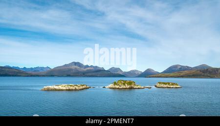 Die drei winzigen Inseln Eilean Ruairidh in Loch Eishort mit den Cuillin-Bergen in der Ferne, aus Sicht von Tokavaig, Isle of Skye, Schottland Stockfoto