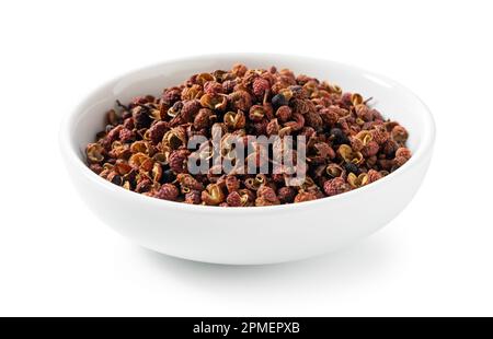 Sichuanpfeffer in einer weißen Schüssel vor weißem Hintergrund. Sichuan-Pfeffer ist ein Mitglied der Familie Sansho, die beim chinesischen Kochen verwendet wird. Stockfoto