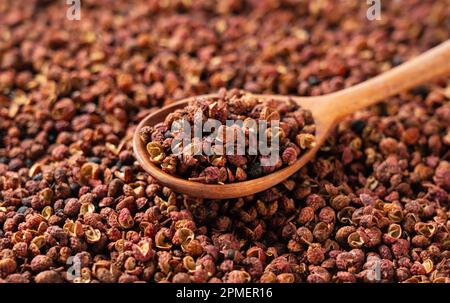 Sichuanpfeffer und Holzlöffel auf dem Bildschirm. Sichuan Pfeffer ist ein Mitglied der Familie Sansho, die in der chinesischen Küche verwendet wird. Stockfoto