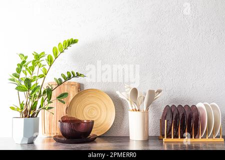 Verschiedene umweltfreundliche Küchenutensilien aus Holz und Glas auf der Küchenarbeitsfläche. Inneneinrichtung einer modernen Küche. Innenblume. Stockfoto