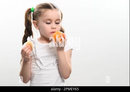 Tangerinen und Chips, gesund und schädlich, ein Mädchen mit einer Tangerine und Chips in den Händen auf weißem Hintergrund. Stockfoto