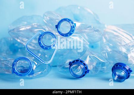 Viele leere Plastikflaschen auf blauem Hintergrund. Abfall- und Verschmutzungskonzept. Stockfoto