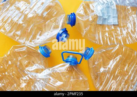 Viele leere, verdorbene Flaschen aus Plastik auf gelbem Hintergrund. Abfall- und Verschmutzungskonzept. Stockfoto