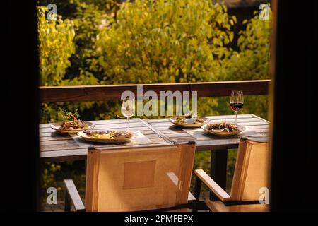 Abendessen im Freien auf der Sommerterrasse. Serviert wird ein Tisch mit mehreren Gerichten. Leckeres Essen im Restaurant. Ansicht von innen Stockfoto