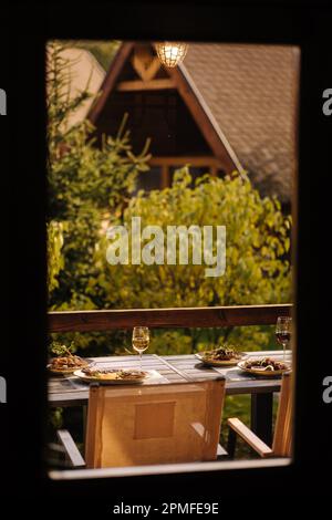 Abendessen im Freien auf der Sommerterrasse. Serviert wird ein Tisch mit mehreren Gerichten. Leckeres Essen im Restaurant. Ansicht von innen Stockfoto