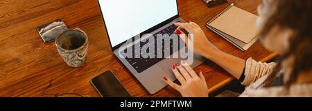 Nahaufnahme einer Freiberuflerin, die an seinem Arbeitsplatz zu Hause an einem Laptop arbeitet Stockfoto