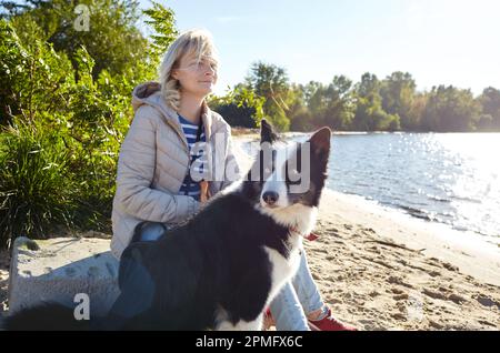 Besitzer mit einem sibirischen laika Hund am Strand. Freundschaft zwischen Hund und Frau Stockfoto