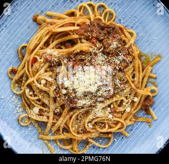 Pasta Bolognese auf blauem Teller isoliert auf schwarzem Hintergrund, Draufsicht Stockfoto