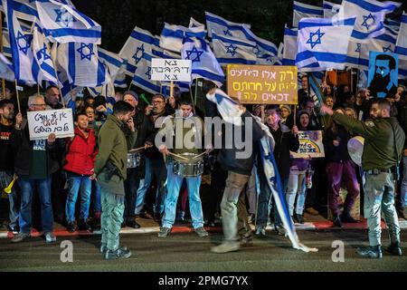 Hadera, Israel. 12. April 2023. Grenzpolizisten stehen während der Demonstration vor Demonstranten, die gegen die Reform sind und die die israelische Flagge und ein Schild mit der Aufschrift „Sie haben kein Mandat, das Gericht zu kontrollieren“, „Be Gone DyBIBIbuk“ und „nur diejenigen, die wissen, wie sie ihre Freiheit schützen können, haben Anspruch darauf“ tragen. Demonstranten für und gegen die Justizreform in Hadera demonstrieren vor einer Mimouna-Zeremonie unter Teilnahme von Ministerpräsident Benjamin Netanjahu, dass es Konfrontationen zwischen reformfeindlichen Demonstranten und reformfreundlichen rechtsgerichteten Aktivisten gab. Kredit: SOPA Images Limited/Alamy Live News Stockfoto