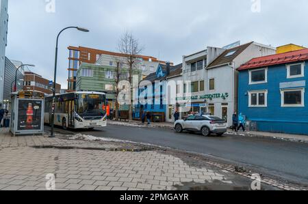 In Tromso, Norwegen, fährt ein öffentlicher Bus entlang einer Stadtstraße mit Menschen und Gebäuden Stockfoto