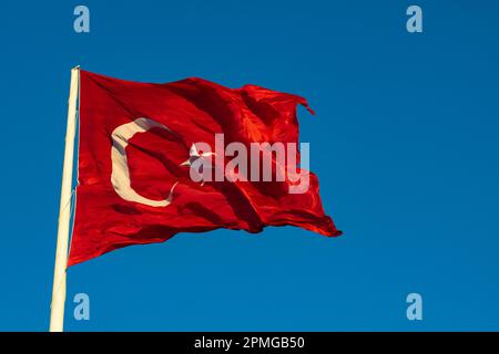 Bei Sonnenuntergang mit der türkischen Flagge auf blauem Hintergrund. Gesetzliche Feiertage in Turkiye. Turk bayragi auf Türkisch. Stockfoto