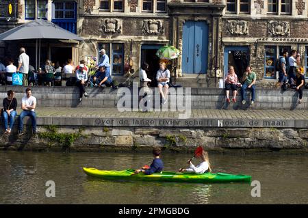 Touristen in canoo in Graslei an der Leie mit einer Gruppe von Personen, die sich in Gent, Flandern, Belgien, entspannen Stockfoto