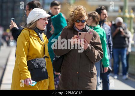 London, Großbritannien. 12. April 2023. Eine Frau auf der Westminster Bridge in London sieht auf ihr Handy. (Foto: Steve Taylor/SOPA Images/Sipa USA) Guthaben: SIPA USA/Alamy Live News Stockfoto