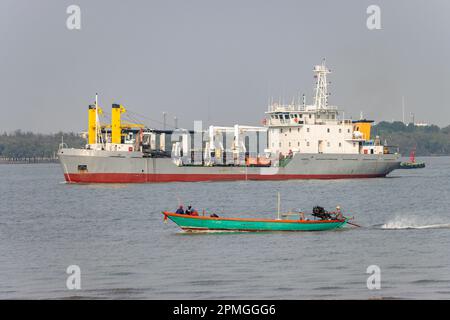 Ein Fischerboot segelt auf dem Chao Phraya River, ein Baggerboot im Hintergrund, Thailand Stockfoto