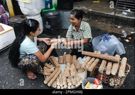 01.08.2013, Rangun (Yangon), Myanmar, Asien – eine alltägliche Marktszene zeigt eine Frau, die Thanaka-Holz auf einem Straßenmarkt im Stadtzentrum einkauft. Stockfoto