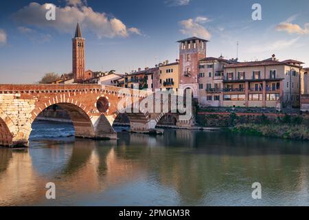 Verona, Italien. Stadtbild der wunderschönen italienischen Stadt Verona mit Steinbrücke über dem Fluss Adige bei Sonnenuntergang. Stockfoto