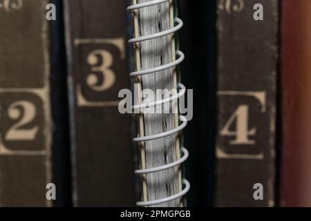 Ein federbelastetes Notizbuch inmitten alter brauner Bücherbände, Nahaufnahme Makroansicht Stockfoto