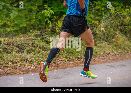 Chelyabinsk, Russland - 11. September 2016: Beine männlicher Läufer läuft Marathon im Road City Park. Asics Laufschuhe und Handschuhe, Mizuno Kompressionssocken Stockfoto