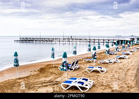 Liegestühle und Sonnenschirme stehen an einem einsamen Strand Stockfoto