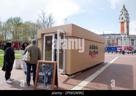 London, UK, 13. April 2023: Am Windrush Square, Brixton, ist ein riesiger Schuhkarton eingetroffen, der eine Pop-up-Ausstellung „Walk a Mile in My Shoes“ am Empathy Museum zeigt. Besucher wählen ein Paar Schuhe und hören sich eine Aufzeichnung des Schuhbesitzers an, in der sie über ihre Erfahrungen mit dem Brixton-Aufstand von 1981 oder anderen Aufständen in Bristol und Liverpool in dieser Zeit sprechen. Anna Watson/Alamy Live News Stockfoto