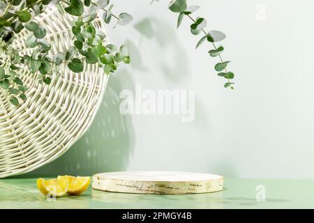 Leeres Holzpodium mit Zitronenscheiben auf blauem Hintergrund mit Eukalyptuslaub Stockfoto