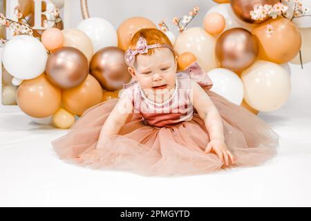 Das kleine weinende, unglückliche rothaarige Baby-Mädchen feiert den ersten Geburtstag. 1 Jahre Familienparty professionelles Fotoshooting im Fotostudio. Süße adora Stockfoto