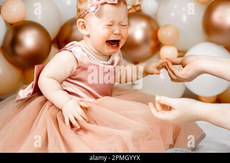 Das kleine weinende, unglückliche rothaarige Baby-Mädchen feiert den ersten Geburtstag. 1 Jahre Familienparty professionelles Fotoshooting im Fotostudio. Süße adora Stockfoto