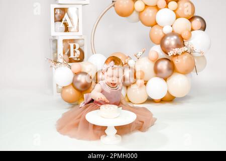 Das kleine rothaarige Mädchen feiert den ersten Geburtstag. Kuchenabsturz, Hände essen. 1-jährige Familienparty. Professionelles Fotoshooting. Fotostudio Stockfoto