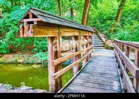 Die alte hölzerne Fußgängerbrücke mit einem Damm auf einem kleinen Fluss im Sofiyivsky Park, Uman, Ukraine Stockfoto