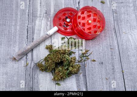 Medizinisches Marihuana Knospen einen Joint und einen roten Plastikschleifer Stockfoto