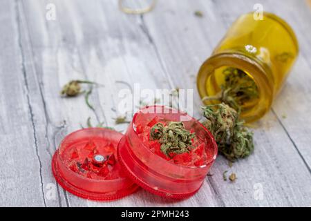 Medizinische Marihuana-Knospen in einer Flasche und ein rotes Plastikmahlwerk Stockfoto