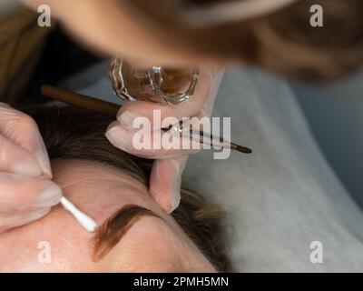 Nahaufnahme der Hand des Kosmetikers mit bürstenfarbenen Augenbrauen im Schönheitssalon Stockfoto
