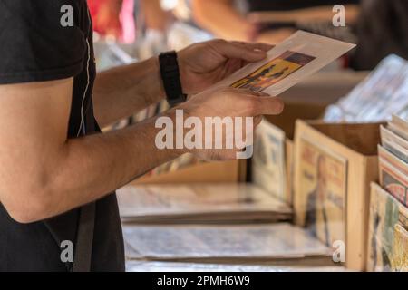 Selektiver Fokus auf die rechte Hand eines unbekannten Mannes auf einem Flohmarkt auf der Suche nach Schallplatten. Stockfoto