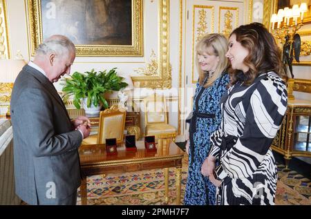 König Karl III. Erhält die erste geprägte £5-Krönungsmünze von Anne Jessopp, CEO der Royal Mint (Zentrum), und Regisseurin Rebecca Morgan (rechts) im Schloss Windsor, Berkshire. Ein gekröntes Porträt des Königs wird zum ersten Mal auf einer neuen Reihe von Gedenkmünzen erscheinen, die zur Feier der bevorstehenden Krönung entworfen wurden. Die Kollektion, die eine 50p- und £5-Euro-Münze enthält, wird im Laufe des Monats vor der historischen Feier am 6. Mai veröffentlicht. Foto: Donnerstag, 13. April 2023. Stockfoto