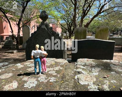 Ein blondes Paar Miniaturmenschen besucht den Friedhof. Das Konzept von Tod und Verlust und die Zukunft. Stockfoto