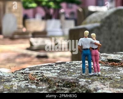 Ein blondes Paar Miniaturmenschen besucht den Friedhof. Das Konzept von Tod und Verlust und die Zukunft. Stockfoto