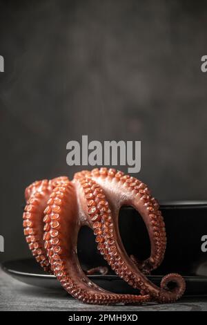 Low-Key-Fotografie des gekochten Oktopus auf der Platte, Platz für Text Stockfoto