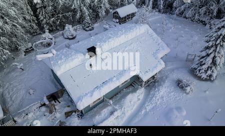 Luftaufnahme eines freistehenden Hauses mit verschneiten Photovoltaikzellen auf dem Dach Stockfoto