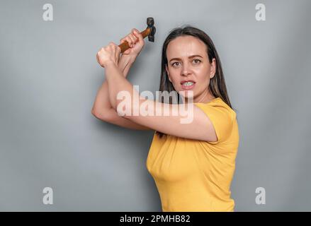 Die Frau hält sich in den Händen und schwingt den Schirm. Weibliche Wut Stockfoto