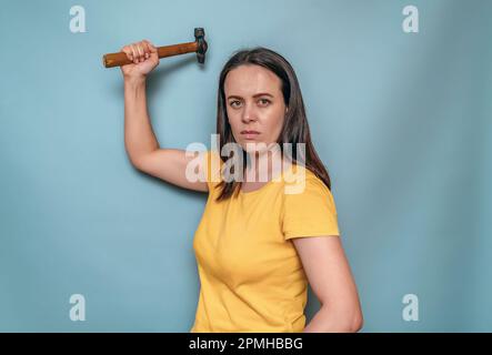 Die Frau hält sich in den Händen und schwingt den Schirm. Weibliche Wut Stockfoto