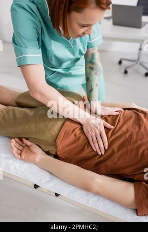 Manueller Therapeut massiert schmerzhaften Rücken eines Mannes im Aufwachzentrum, Stockbild Stockfoto