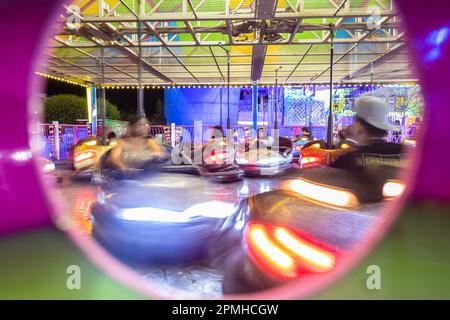 Autoskooter auf einem Jahrmarkt, der mitten in Bewegung ist, während unbekannte Menschen die Fahrt genießen. Stockfoto